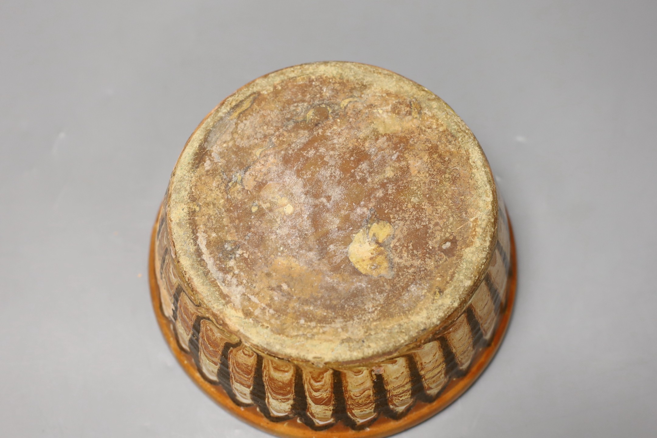 A Slipware conical bowl, 18th / 19th century, flaking to decoration, 19cm diameter, together with a pair of German faience flower decorated bough pots, late 18th century, 15.5cm wide